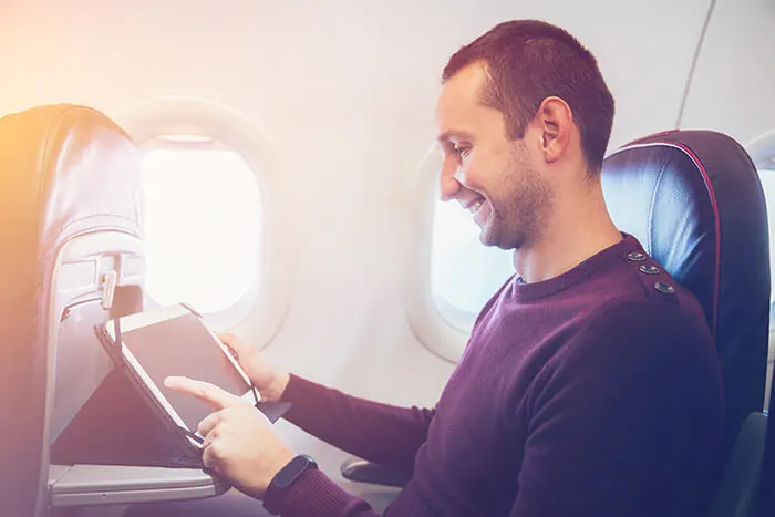 Young man using his tablet on a plane